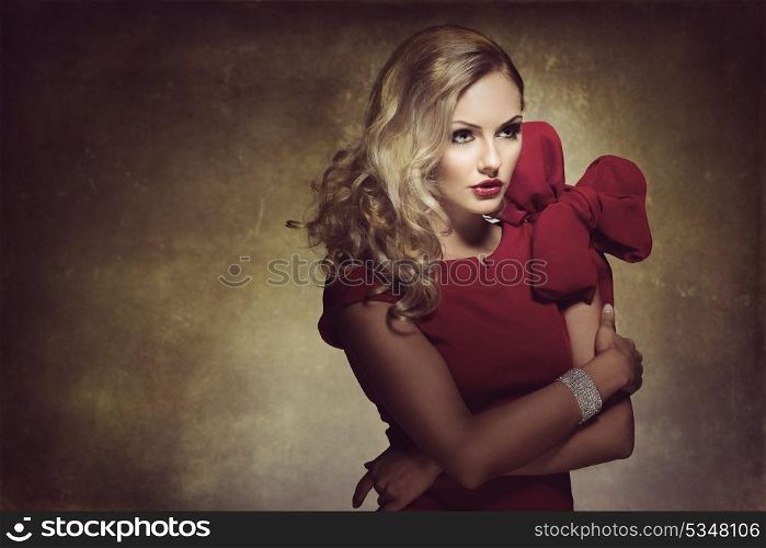 blond young woman in red dress and creative hair style , looking on one side. she has a big bow