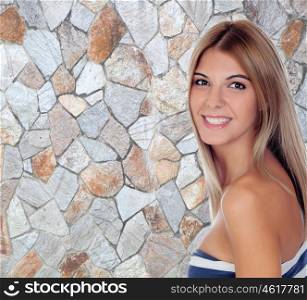 Blonde attractive girl smiling with a stone wall of background