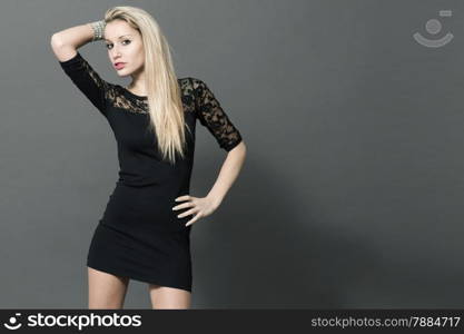 Blonde beautiful woman with black dress posing over grey background