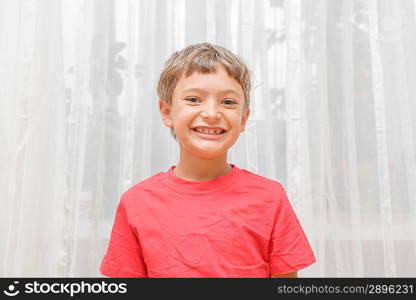 Blonde boy in a red shirt indoors