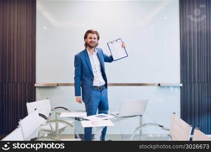 Blonde business man holding blank paper on blank glass board