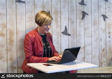 Blonde business woman using laptop while sitting in a cafe