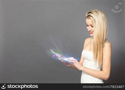 Blonde caucasian woman standing with tablet over grey background