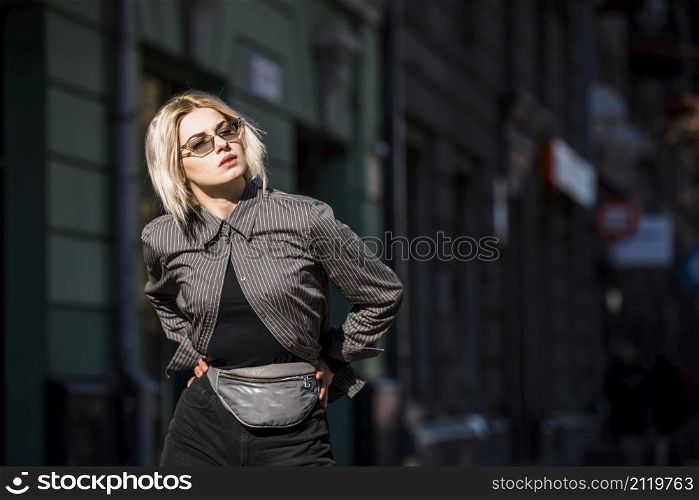 blonde fashionable young woman with hand hips looking away