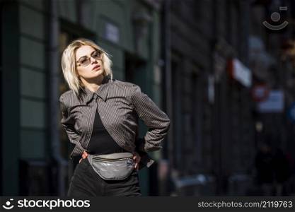 blonde fashionable young woman with hand hips looking away
