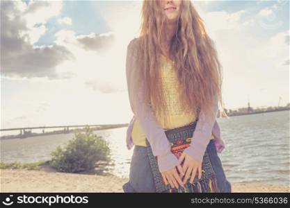 blonde girl against sky, sea and coast. Part of the body shot