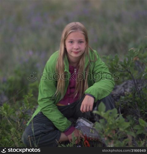 Blonde girl crouching in field