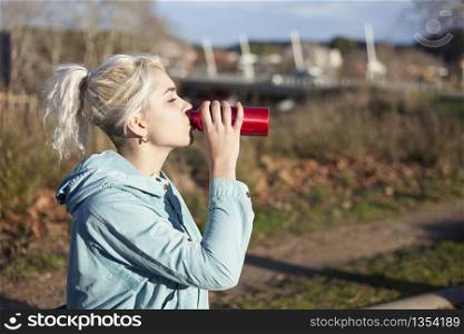 Blonde girl drinking water during morning jogging