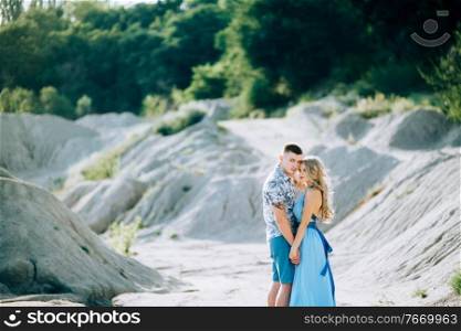 blonde girl in a light blue dress and a guy in a light shirt and short shert in a granite quarry