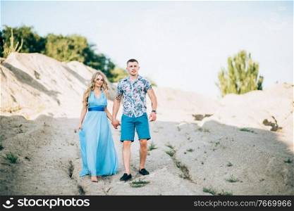 blonde girl in a light blue dress and a guy in a light shirt and short shert in a granite quarry