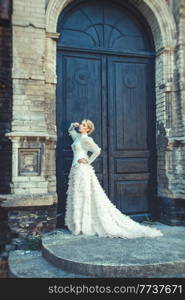 Blonde girl in a retro dress on the background of the old dark door of the building
