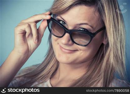Blonde girl in sunglasses, closeup portrait. Studio shot on blue background. Vintage filter