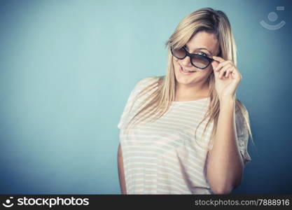 Blonde girl in sunglasses, portrait. Studio shot on blue background. Vintage filter