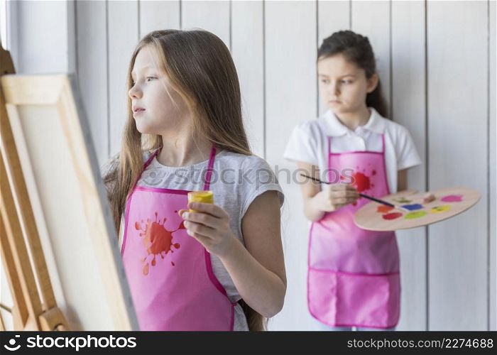 blonde girl painting easel her friend standing background