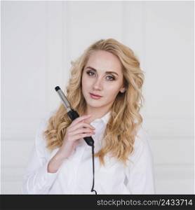 blonde girl posing with curling iron