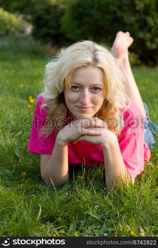 blonde girl resting on the green grass