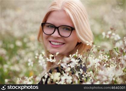 Blonde girl with glasses in the field surrounded by flowers