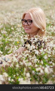 Blonde girl with glasses in the field surrounded by flowers