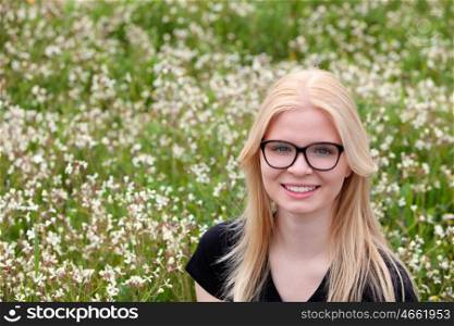 Blonde girl with glasses in the field surrounded by flowers