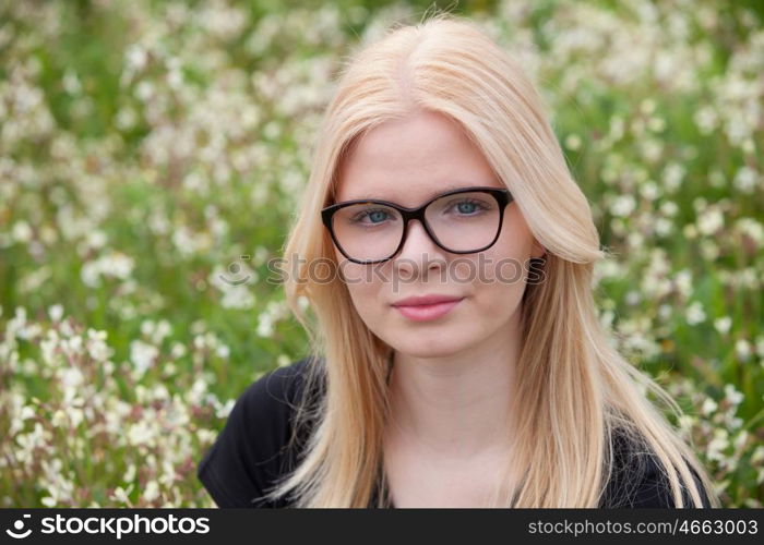 Blonde girl with glasses in the field surrounded by flowers