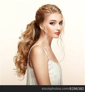 Blonde Girl with Long and shiny Curly Hair. Beautiful Model Woman with Curly Hairstyle. Care and Beauty Hair products. Perfect Make-Up