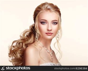 Blonde Girl with Long and shiny Curly Hair. Beautiful Model Woman with Curly Hairstyle. Care and Beauty Hair products. Perfect Make-Up and Jewelry