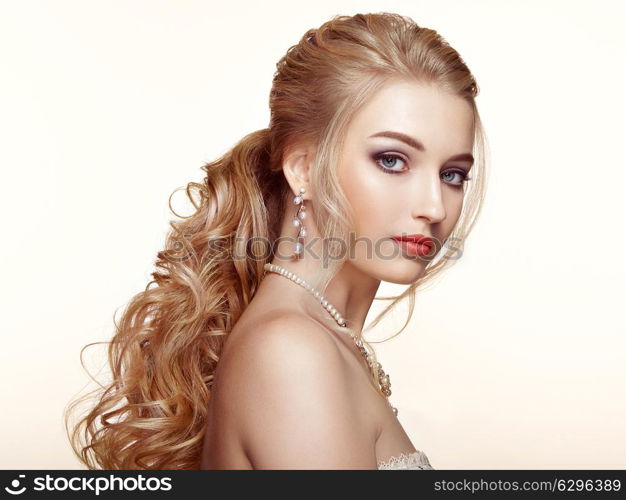 Blonde Girl with Long and shiny Curly Hair. Beautiful Model Woman with Curly Hairstyle. Care and Beauty Hair products. Perfect Make-Up and Jewelry