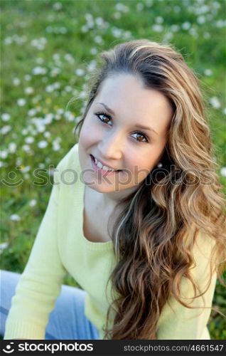 Blonde girl with many daisies around looking at camera