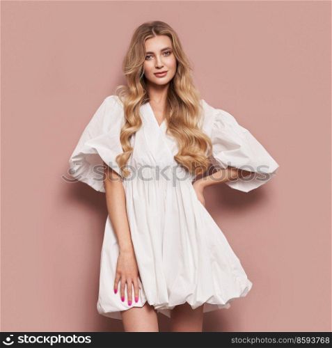 Blonde girl with perfect makeup. Smiling beautiful model woman with long curly hairstyle. Care and beauty hair products. Model in white festive dress