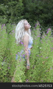Blonde haired woman in long grass and flowers