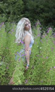 Blonde haired woman in long grass and flowers