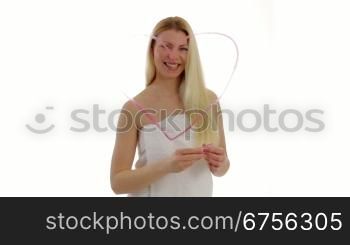 Blonde junge Frau mal ein Herz mit Lippenstift auf eine Glasscheibe.Young blonde woman paints a heart with lipstick on a window pane.