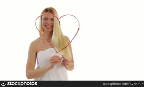 Blonde junge Frau mal ein Herz mit Lippenstift auf eine Glasscheibe.Young blonde woman paints a heart with lipstick on a window pane.