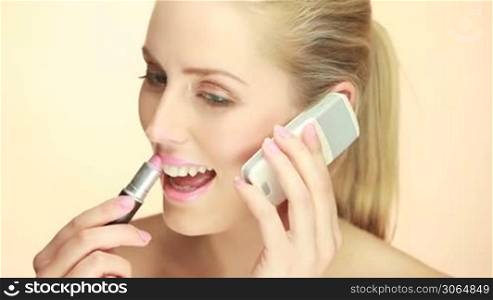 Blonde Lady Using Mobile Phone and applying lipstick