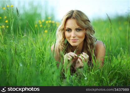 blonde lays on green grass