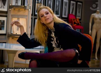 Blonde leans elbow on Tulip table in appartment gallery