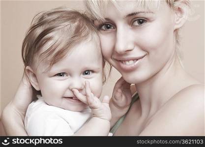 Blonde mother holds baby with hand in mouth