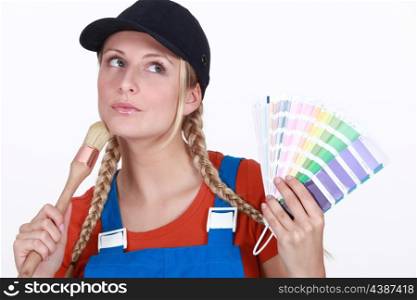 blonde painter looking inspired holding color chart and brush