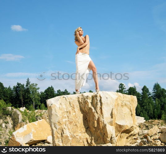 Blonde posing on the giant and sharp rock