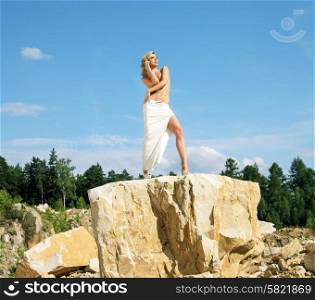 Blonde posing on the giant and sharp rock