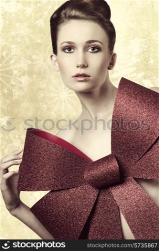 blonde sexy woman with elegant hair-style adorned with big red glitter bow posing in christmas shoot