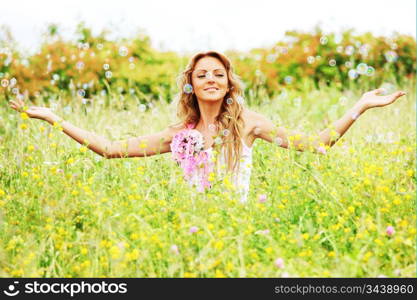 Blonde starts soap bubbles in a green field