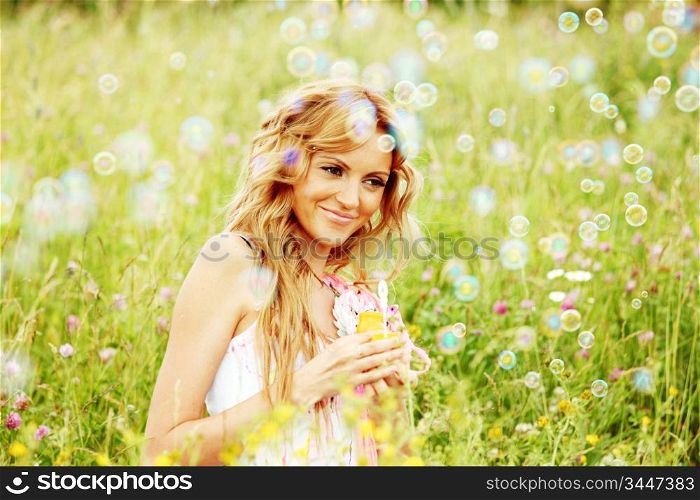 Blonde starts soap bubbles in a green field