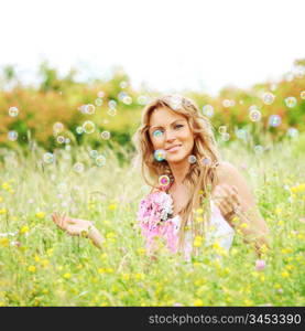 Blonde starts soap bubbles in a green field