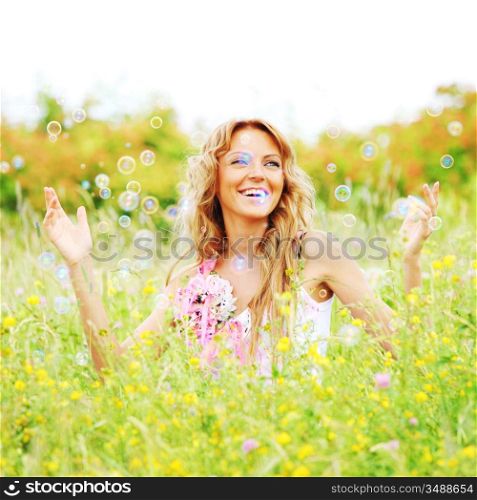 Blonde starts soap bubbles in a green field