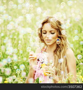 Blonde starts soap bubbles in a green field