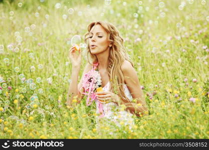 Blonde starts soap bubbles in a green field