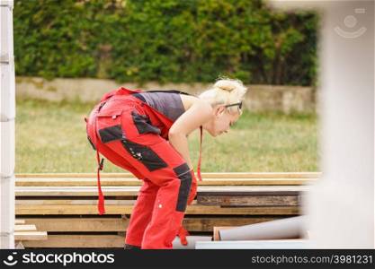 Blonde strong woman in dungarees working on home construction site. Women power, gender equality, industrial worker.. Woman in dungarees working on construction site