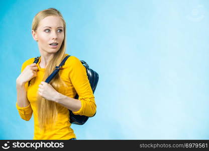 Blonde teenage girl going to school or college wearing stylish backpack. Outfit trendy accessories. On blue. Teen girl with school backpack