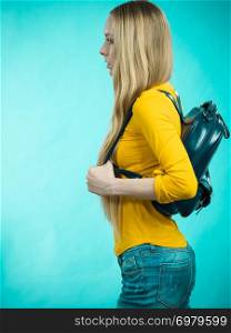 Blonde teenage girl going to school or college wearing stylish backpack. Outfit trendy accessories. On blue. Teen girl with school backpack